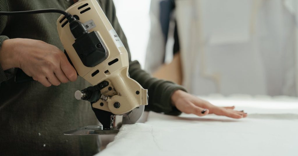 Close-up of hands using a rotary cutter to cut fabric in a sewing workshop.